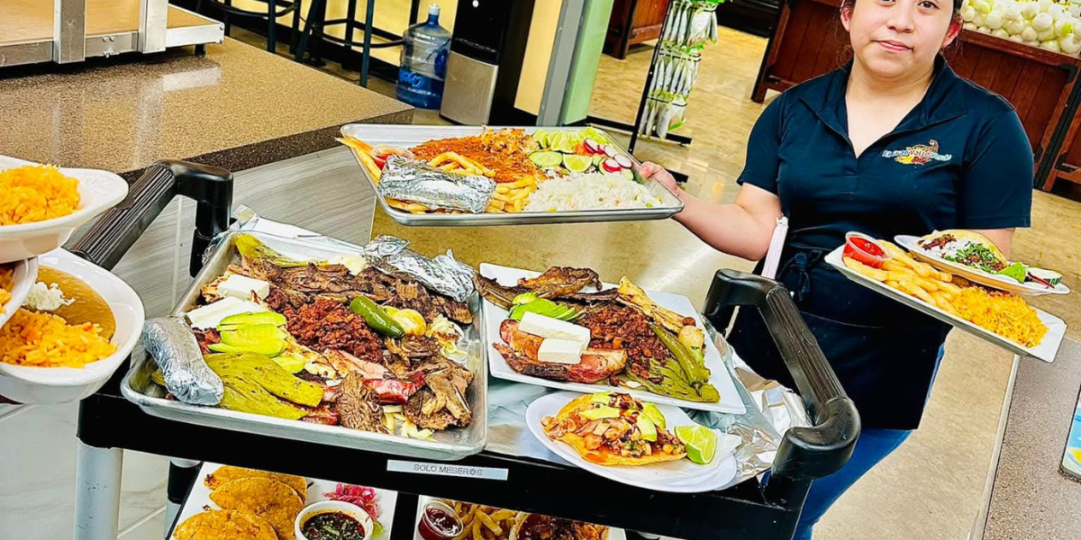 Large platters of authentic Mexican food including tacos, rice, beans, and grilled meats served inside the Taquería at El Gran Valle Verde in Hamilton, Ohio.